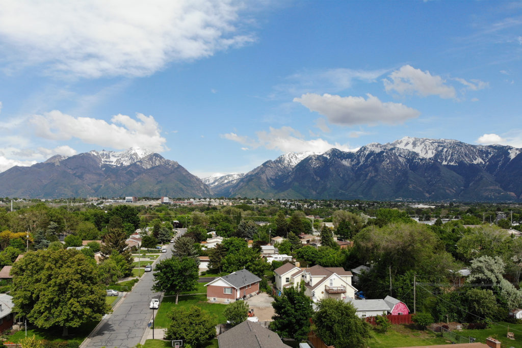 Aerial View of Neighborhood and Wasatch Mountains Aerial view of a residential neighborhood with the Wasatch Mountains in the background on a partly cloudy day.