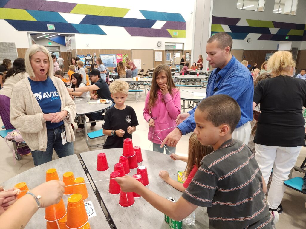 Andrew at School Family Event Andrew helping students with a cup-stacking activity during a school event in the cafeteria.