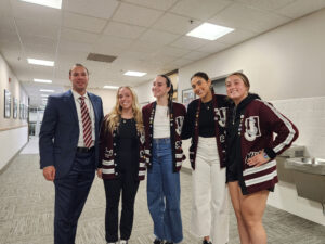 Meeting with Jordan High Student Leaders Andrew Edtl stands with four Jordan High School student leaders in school letterman sweaters inside a district hallway.
